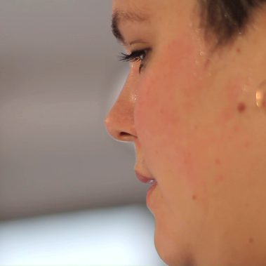 A woman's face facing away from the camera. You can just see her side profile, her hair is short.