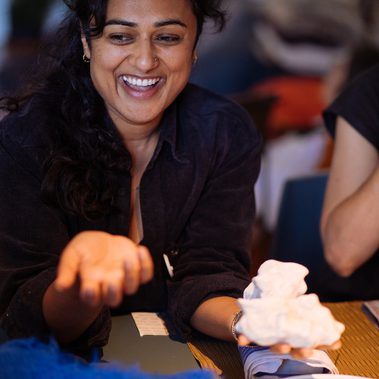 A woman is laughing as she holds out both hands, one is empty, the other has what looks like a small cloud in it.