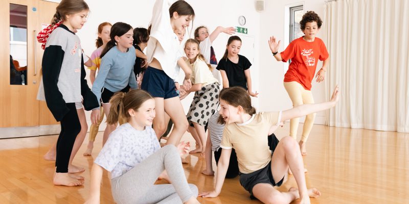 Children around 10 year olds having fun in a dance studio.