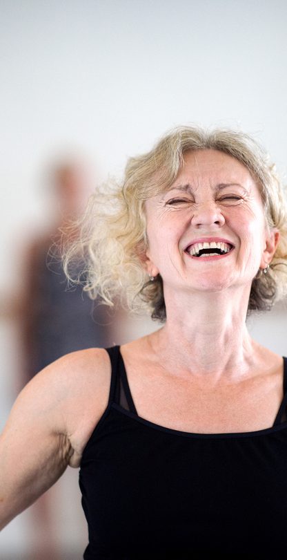 An over 60s dance class participant laughing in a dance studio