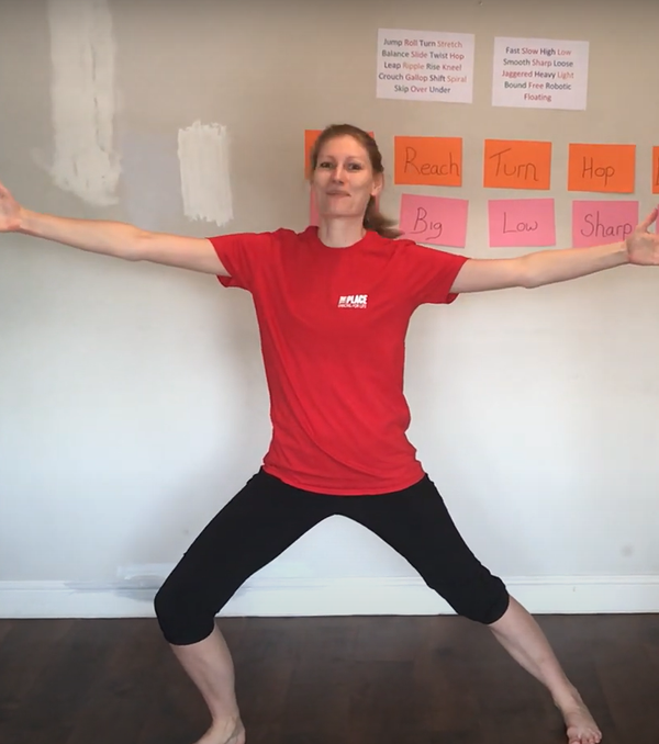 Person in a room wearing a red t-shirt and black leggings. The are stretching out their arms and legs to their side.