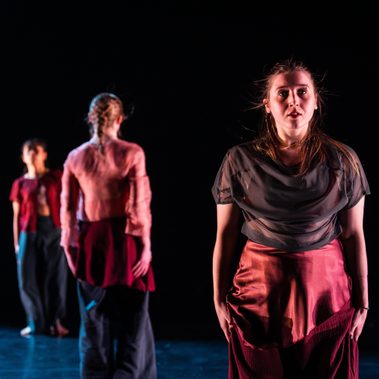 Three students at the Peggy Hawkins Gala stand in a row, 2 face forward and one faces to the back.