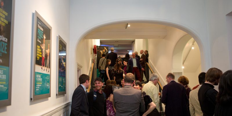 Busy stairwell to The Place bar on the way into the theatre. Lots of people are standing and talking