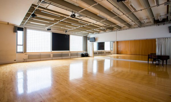 Image of an empty studio with wooden floors and windows on the left