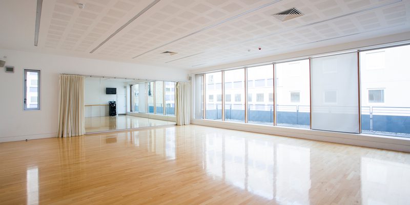 image of an empty studio with large windows on the right hand side and mirrors on the left