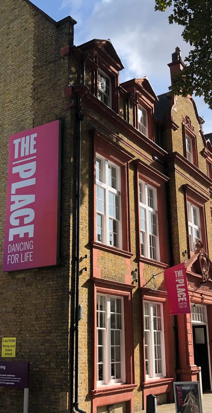 The Place building on Duke's Road from the side with a branded pink banner