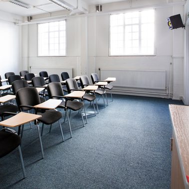 Photo taken from a corner facing 3 rows of individual chairs with desks facing a screen.