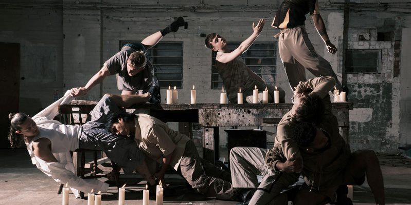 Six individuals positioned around a table surrounded by candles