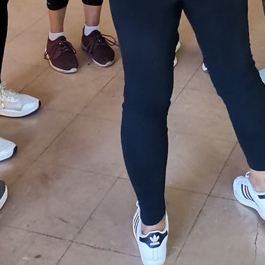 A circle of feet and legs of women wearing leggings and trainers.