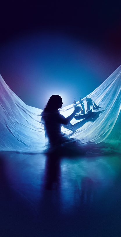 Silhouette of Little M, a Silhouette of Little M, a person with long hair, wearing a draped flowing translucent fabric, holding a model ship with red sails. Backlit to create a dreamy, underwater-like glow, the image evokes a sense of a dreamlike world. with long hair, wearing a draped flowing translucent fabric, holding a model ship with red sails. Backlit to create a dreamy, underwater-like glow, the image evokes a sense of a dreamlike world.