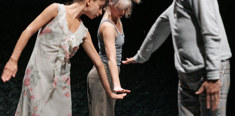 Image of three dancers dancing in front of a black background