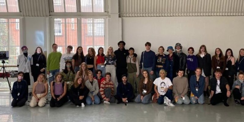 This is an image of LCDS BA1 students from 2021. A line of dancers sit down across the image. Another line of dancers stand up behind the ones sitting down.