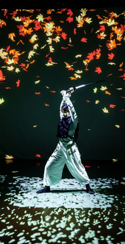 Female swordfighter in front of falling autumn leaves