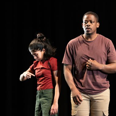 The performers are pointing to themselves, with one of them looking forward to the audience, and the other turned diagonally looking down.