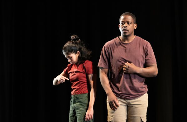 The performers are pointing to themselves, with one of them looking forward to the audience, and the other turned diagonally looking down.