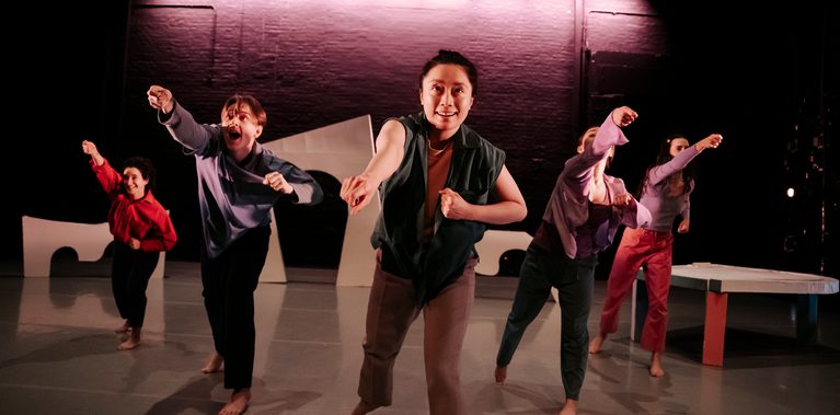 Five dancers energetically reach forward, their expressions animated and focused.