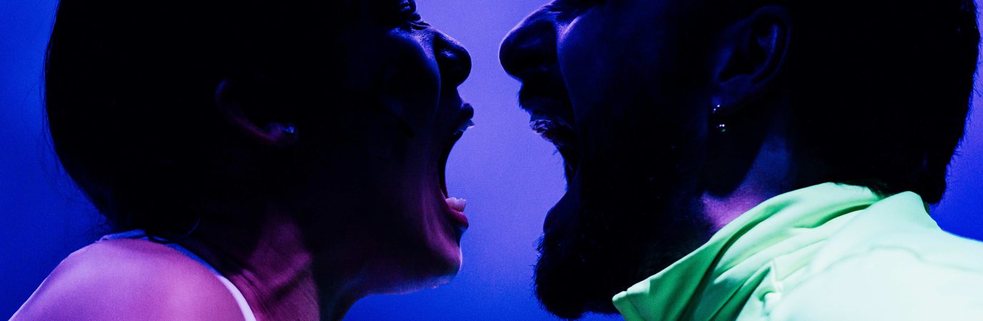 A woman and a man shouting into each others' mouths.