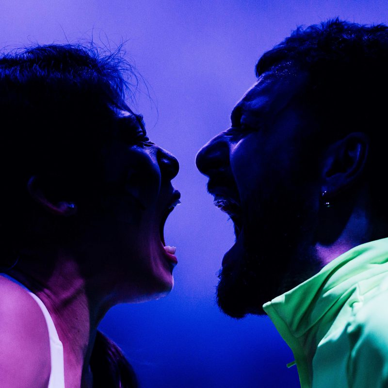 A woman and a man shouting into each others' mouths.