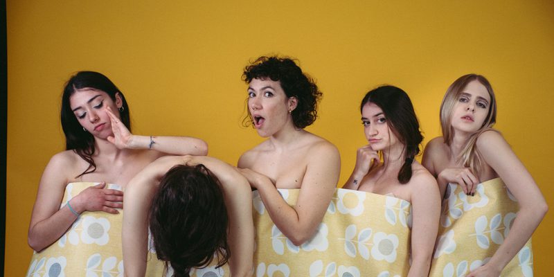 Image of five dancers standing in a line with a piece of wallpaper connecting them