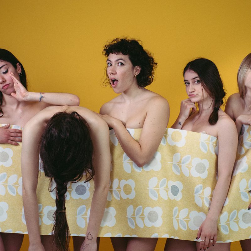 Image of five dancers standing in a line with a piece of wallpaper connecting them