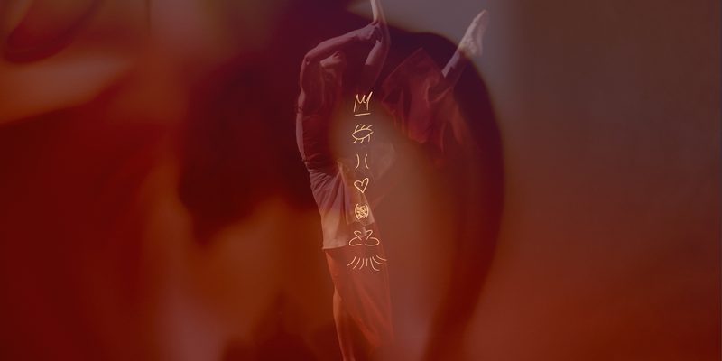 A double-exposure image in warm red and brown tones features a dancer in mid-motion overlaid with a soft, floral silhouette. A vertical stack of golden line-art symbols, including a crown, an eye, and a heart, is centered over the figure.