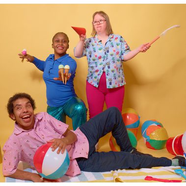 Three performers pose with props from the show ice cream cones a seagull beak and a beach ball