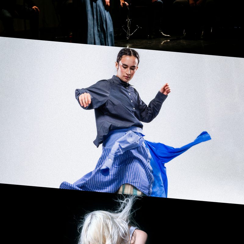 This image is divided into three parts. On the top, woman standing on stage in front of a group of musicians, wearing a long dark skirt and white jacket, captured in between movements with her arms by her sides. In the centre, person wearing a navy shirt and two blue shirts styled as a skirt with red sneakers, caught mid-movement, setting the fabric into motion. On the bottom, a person with long platinum blonde hair covering their face, wearing a white tank top and leather trousers, kneels on grass while holding a leaf blower aimed at their face, setting their hair into motion.