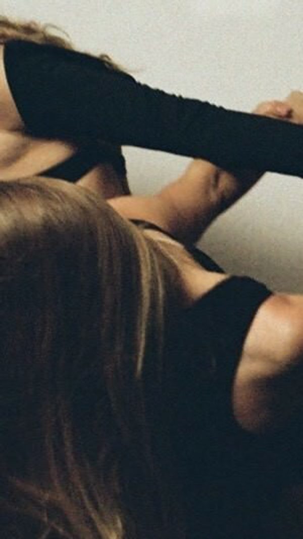 Several dancers in black outfits link arms and hands, their bodies partially visible as they lean and pull in different directions.